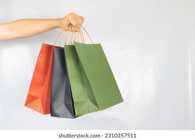 Hand holding paper shopping bag colorful three on white background.