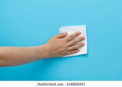 Hand Holding Paper Towel For Cleaning On Blue Background.