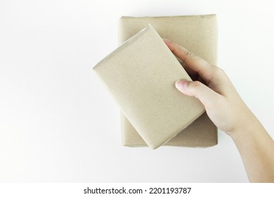 Hand Holding Parcel Boxes For Delivery Or Square Box, Gift Box Wrapped In Brown Paper On White Background.