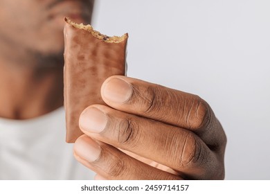 A hand holding a partially eaten protein or granola bar against a white background. - Powered by Shutterstock