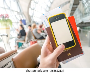 Hand Holding Passport, Boarding Pass And Smart Phone In Airport In Concept Of Going Abroad