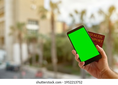 Hand Holding Passport And Smart Phone With Green Screen.Travel Concept With Copy Space. Chroma Key Mockup