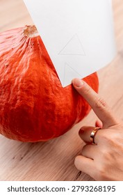 Hand holding pattern preparing pumpkin for Halloween carving