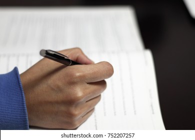 A Hand Holding A Pen Is About To Write Something Down