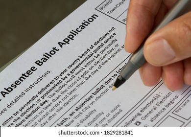 Hand Holding A Pen And Filling Out A New York State Absentee Ballot Application Form. Selective Focus On The Form.