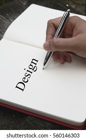 Hand holding pen with a notepad and text Design.