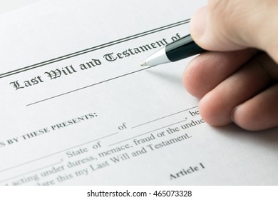 Hand holding pen on last will and testament document - Shutterstock ID 465073328