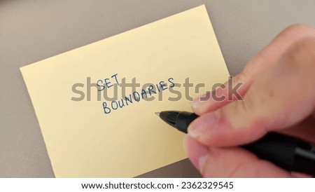 A hand holding a pen, pointing at the words Set Boundaries written on a sticky note
