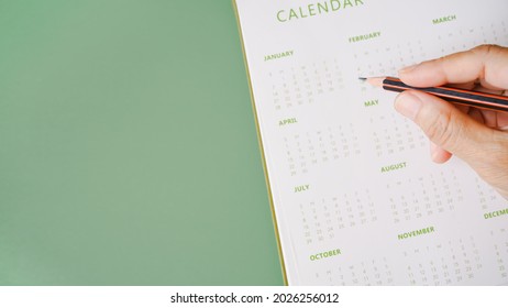 Hand Holding Pencil With Blurred Yearly Calendar For Planning Work ,monthly Or Yearly Schedule , Make Appointment Meeting ,manage Timetable ,routine ,business Project, Timeline Concept
