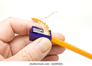 Hand holding pencil sharpener with shavings isolated on white.