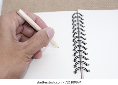 Hand is holding a pencil to write notes.