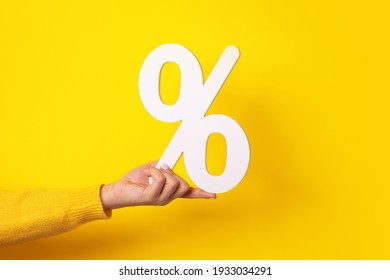 hand holding percentage sign over yellow background