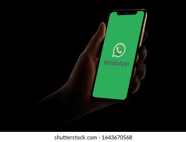 Hand holding phone with the WhatsApp logo in front of a black background. The Facebook-owned app recently hit 2 billion users. It remains ad-free and charge-free.