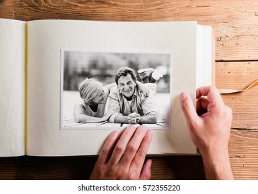 Hand holding photo album with pictures of senior couple. Studio - Powered by Shutterstock