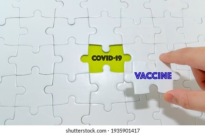 Hand holding piece of jigsaw puzzle with words Covid-19 and Vaccine.