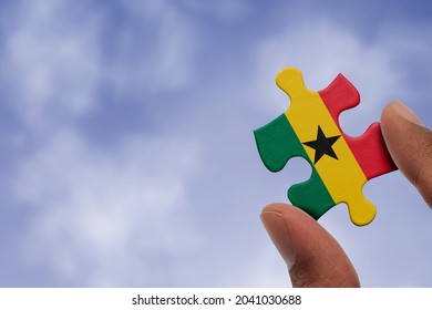 Hand holding piece of jigsaw puzzle with flag of Ghana. Jigsaw puzzle of Ghana flag on sky background. - Powered by Shutterstock