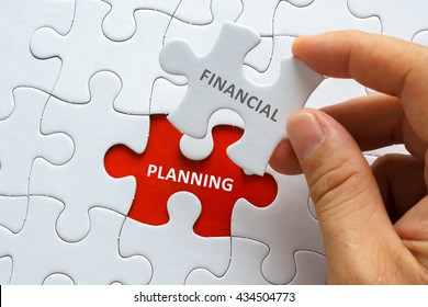 Hand holding piece of jigsaw puzzle with word FINANCIAL PLANNING.