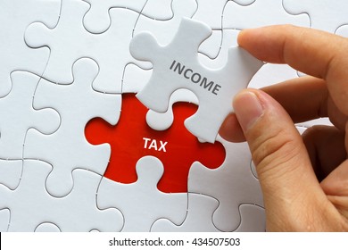Hand holding piece of jigsaw puzzle with word INCOME TAX. - Shutterstock ID 434507503