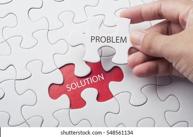 Hand holding piece of jigsaw puzzle with word problem & solution.