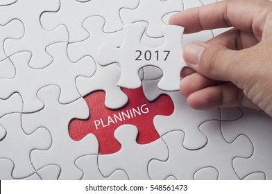 Hand holding piece of jigsaw puzzle with word planning 2017. - Shutterstock ID 548561473