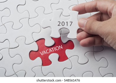 Hand holding piece of jigsaw puzzle with word vacation 2017. - Shutterstock ID 548561476