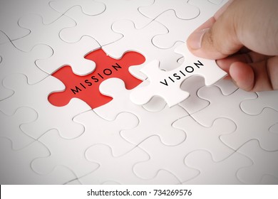 Hand holding piece of jigsaw puzzle with VISION and MISSION wording - Shutterstock ID 734269576