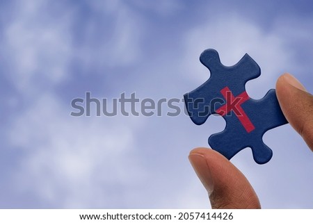 Hand holding piece of jigsaw puzzle with flag of Christianity. Religious symbols of Christianity.
