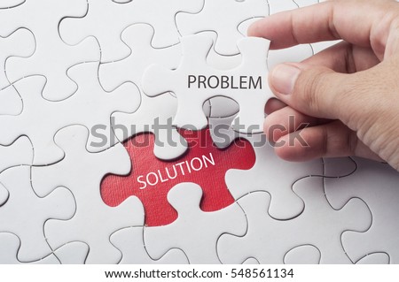 Hand holding piece of jigsaw puzzle with word problem & solution.