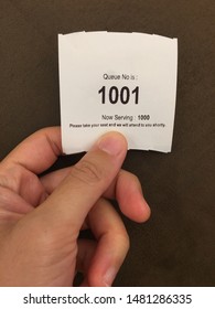 A Hand Holding A Piece Of Queue Number Paper, Being The Next In Line.