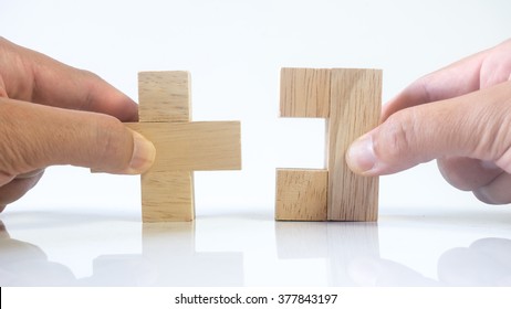 Hand holding piece of wooden block puzzle. Isolated on empty background. Concept of complex and smart logical thinking. Slightly defocused and close up shot. Copy space.