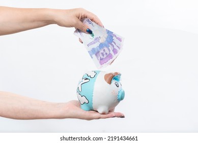 hand holding piggy bank and hand holding Colombian currency bill, money saving concept