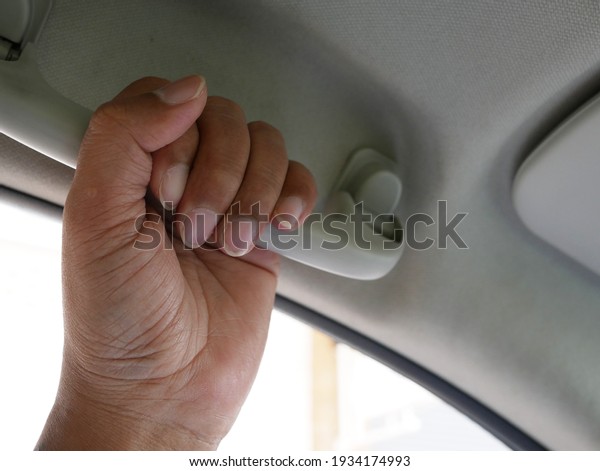 hand holding plastic car grab handle for passenger\
inside the car.
