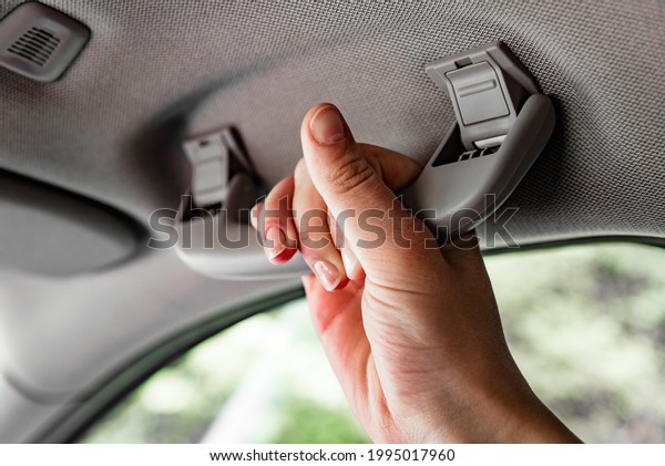 Hand holding plastic car grab handler for the\
passenger in a car.