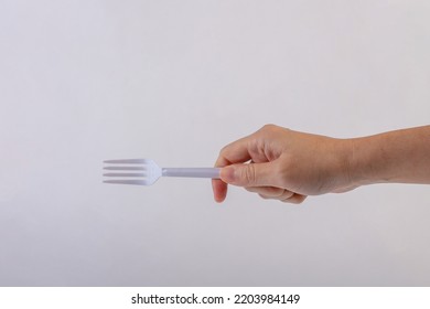 Hand Holding A Plastic Fork On White Background