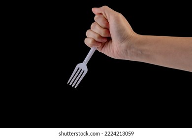 Hand Holding A Plastic Fork On Black Background