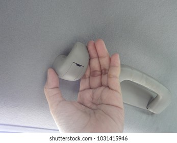 Hand Holding Plastic Hook Of Coat Hanger For Hanging Cloths In A Car.