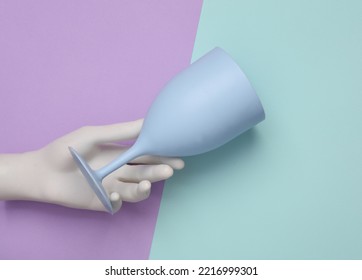 Hand Holding Plastic Wine Glass On Pastel Background. Top View