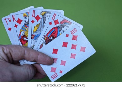 Hand Holding Playing Cards With Royal Flush Combination On Green Background