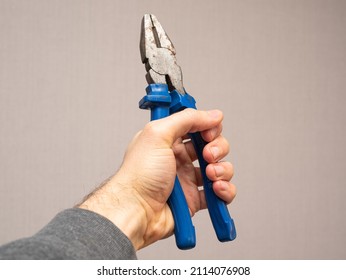 Hand Holding Pliers On Grey Background