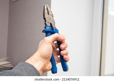 Hand Holding Pliers In The Room