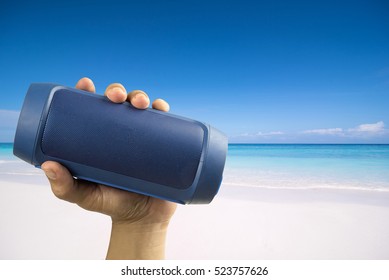 Hand Holding Portable Speaker At The Beach.