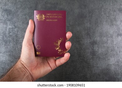 Hand holding Portuguese passport with gray background.