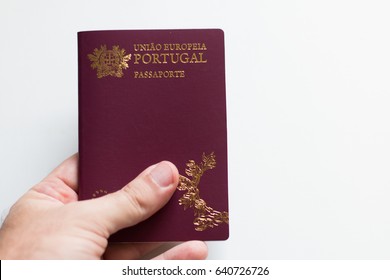 Hand holding portuguese passport on white background
