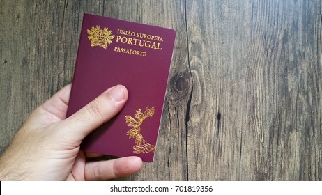 Hand holding Portuguese passport on wooden background