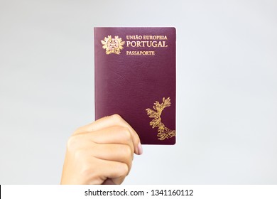 Hand holding  portuguese passport (Translation "European Union Portugal passport") white background.