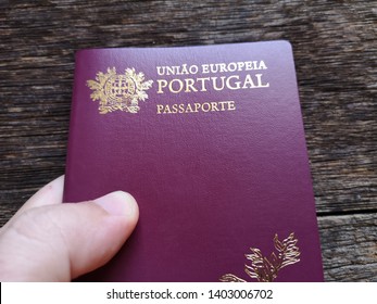 Hand holding Portuguese passport with wooden background