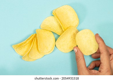 Hand Holding Potato Chips Isolated On Blue Background