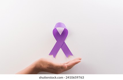 Hand holding purple ribbon on white background for supporting World Cancer Day campaign on February 4.