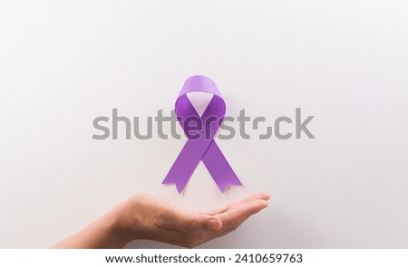 Hand holding purple ribbon on white background for supporting World Cancer Day campaign on February 4.