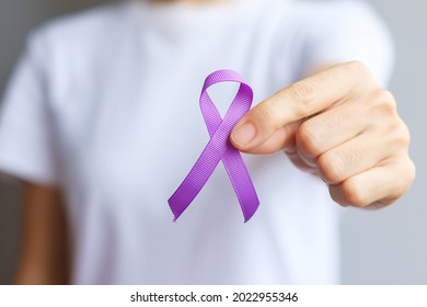 Hand holding purple Ribbon for Pancreatic, Esophageal, Testicular cancer, world Alzheimer, epilepsy, lupus, Sarcoidosis, Fibromyalgia and domestic violence Awareness month. World cancer day concept - Shutterstock ID 2022955346